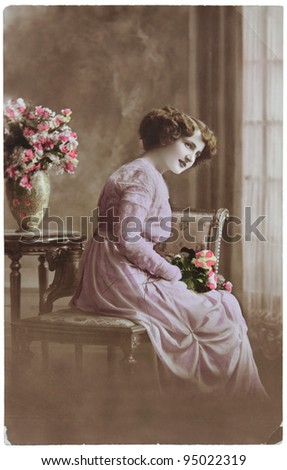 RUSSIA - CIRCA 1906: a vintage postcard printed in Russia shows hand painted photograph of young woman with flowers,  circa 1906.