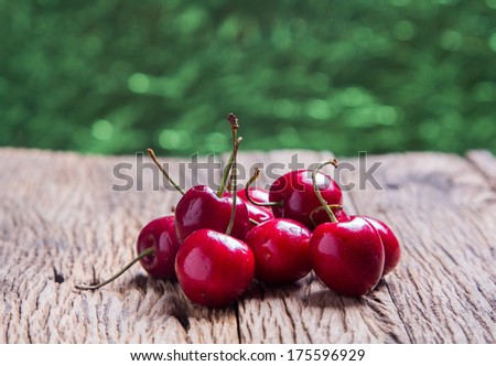 Cherries on wooden table with abstract circular green bokeh background, Close up for design work