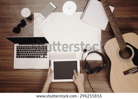 Office desk background, Hand touchscreen on tablet PC with acoustic guitar, headphones recording scene project ideas concept. mobile phones, laptop computer, View from above with copy space