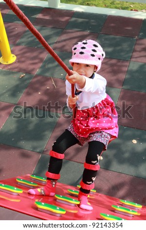 Asian Child girl jungle gym in playground. Outdoor park
