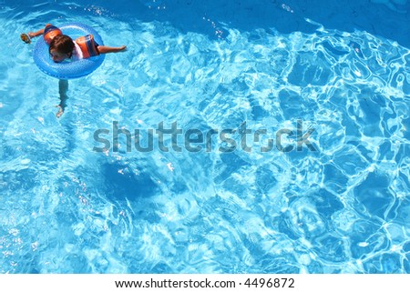 Young girl swimming with arm bands and a ring in a pool all on her own