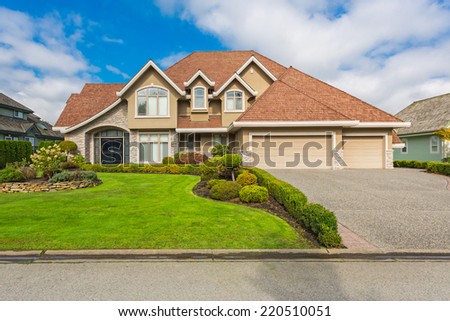 Custom built luxury house with nicely trimmed and designed front yard, lawn in a residential neighborhood. Vancouver Canada.
