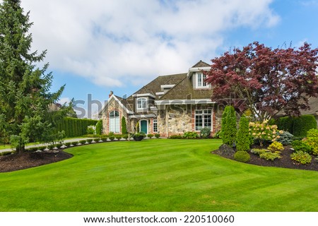 Custom built luxury house with nicely trimmed and designed front yard, lawn in a residential neighborhood. Vancouver Canada.