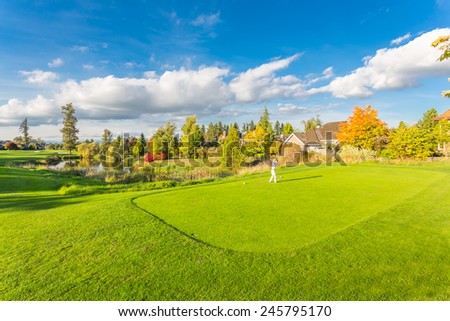 Man playing golf on beautiful sunny green golf course with pond in Vancouver, Canada