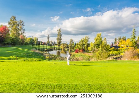 Beautiful sunny green golf course with pond in Vancouver, Canada. A man playing golf.