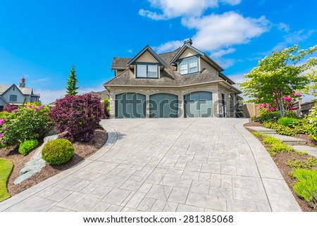 Custom built luxury house with nicely trimmed and designed front yard, lawn in a residential neighbourhood in Canada.