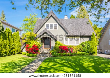 Custom built luxury house with nicely trimmed and designed front yard, lawn in a residential neighborhood in Canada.