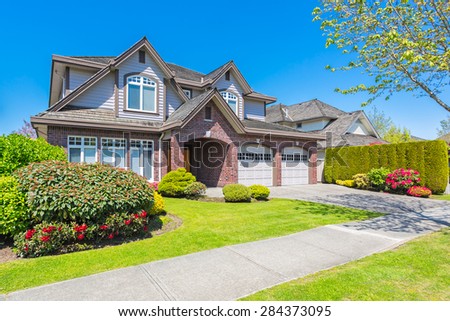Luxury house with nicely trimmed and designed front yard, lawn in a residential neighbourhood in Canada.