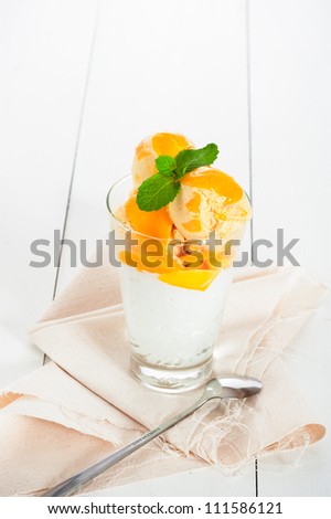 Mango ice cream with fresh mango and whipping cream in a glass