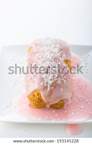 delicious small cake with strawberry icing and coconut topping