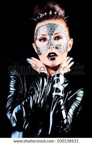 Conceptual shot of a woman in black glossy overall and metal buttons on her face.