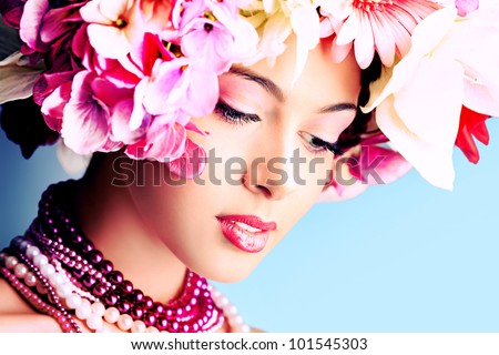Portrait of a beautiful spring girl wearing flowers hat. Studio shot.