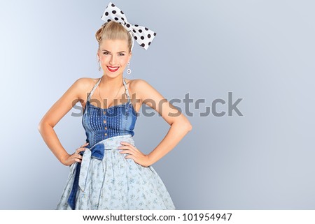 Beautiful young woman with pin-up make-up and hairstyle posing in studio.
