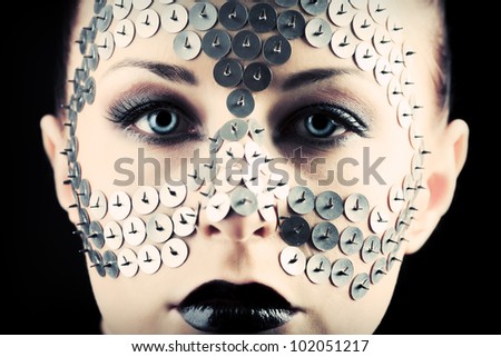 Conceptual shot of a woman with metal buttons on her face.