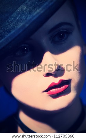 Portrait of the elegant young woman posing in black pot hat. Light and shadow.