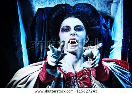 Bloodthirsty female vampire rises from the coffin on the night cemetery.