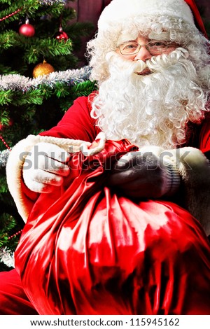 Santa Claus sitting with presents over Christmas background.