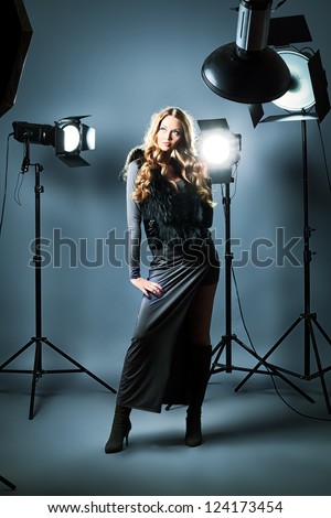 Beautiful female model posing at studio in the light flashes.