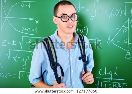 Young man student standing at the blackboard in the classroom.