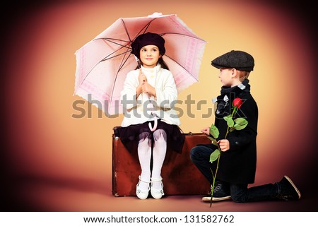 Cute little boy is giving a rose to the charming little lady. Retro style.
