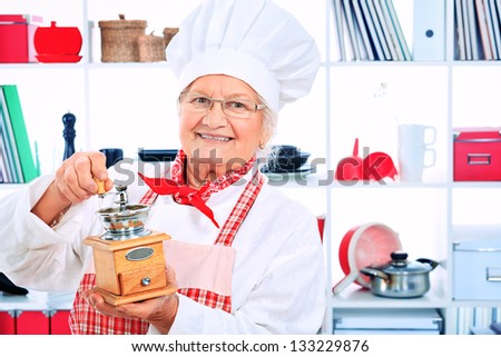 Portrait of a senior woman chef cook grinds coffee with grinder in the kitchen.