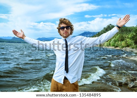 Happy handsome business man standing on a seaside with open arms.
