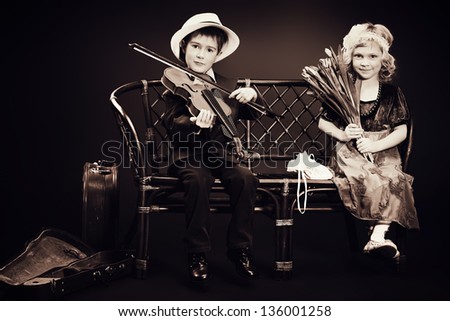 Cute little boy is playing the violin to the charming little lady. Retro style.