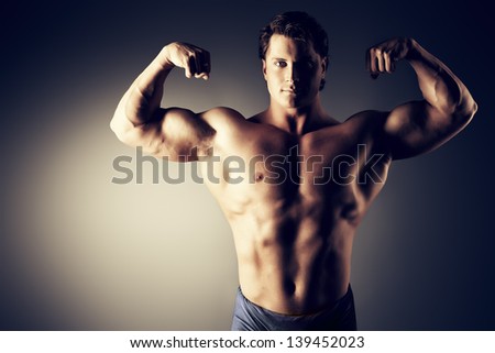 Portrait of a handsome muscular bodybuilder posing over black background.