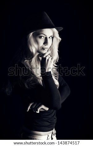 Charming fashion model posing over black background.