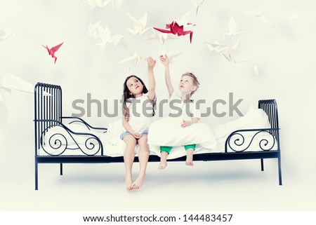 Cute kids sitting together on the bed under the blanket. Dream world.