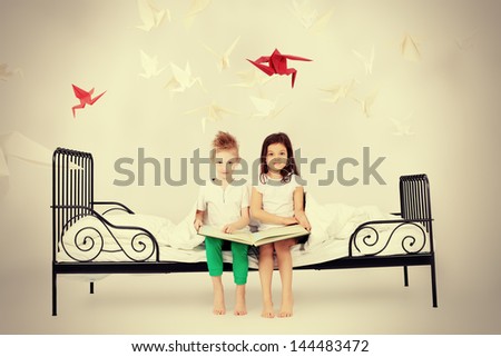 Cute kids sitting together on the bed and reading fairy tales. Dream world.