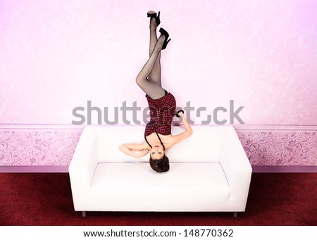 Charming fashionable woman lying on a sofa upside down.
