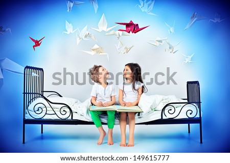 Cute kids sitting together on the bed under the blanket. Dream world.