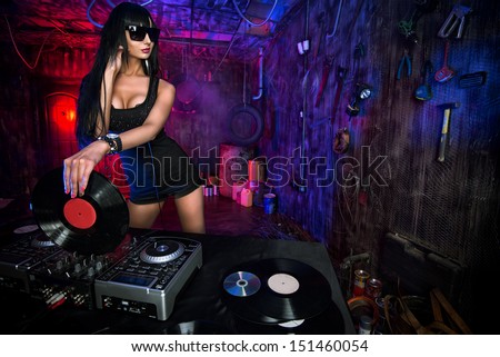 Beautiful sexy DJ girl working on a party in the old garage.