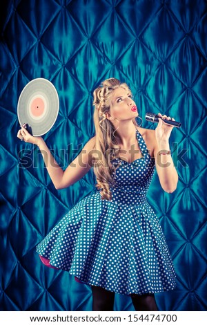 Charming pin-up woman with retro hairstyle and make-up posing with vinyl record.