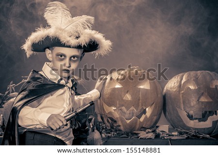 Little boy in halloween costume of pirate posing with pumpkins. Black-and-white.
