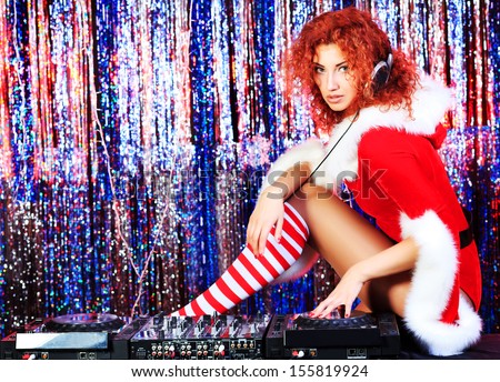 Attractive DJ girl mixing up some Christmas cheer. Disco lights in the background.
