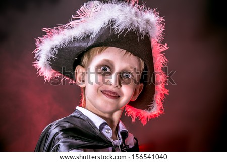 Little boy in halloween costume of pirate posing over dark background.