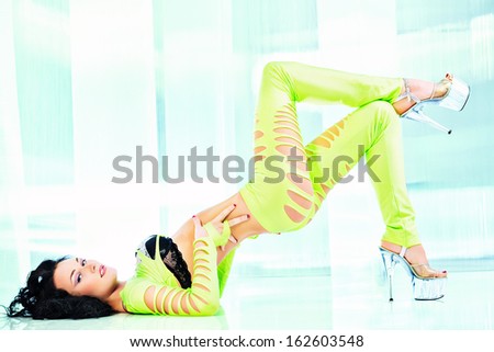 Modern brunette girl dancer in a sexual costume dancing in a futuristic interior.