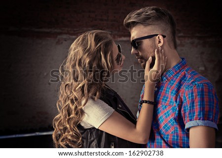 Romantic couple of young people in love posing outdoors over city background.