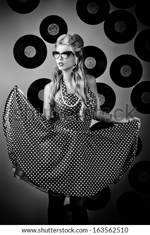 Charming pin-up woman with retro hairstyle and make-up posing with vinyl record.