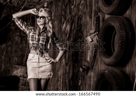Charming pin-up woman with retro hairstyle and make-up in the old garage. Black-and-white.