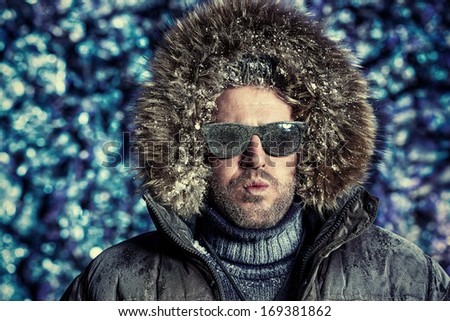 Handsome brutal man dressed in winter clothes covered with frost.