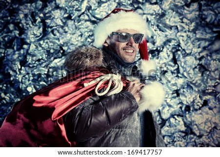 Handsome smiling man dressed in winter clothes and Santa Claus cap covered with frost. Christmas.