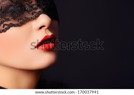 Close-up portrait of a charming  woman in black lace mask.