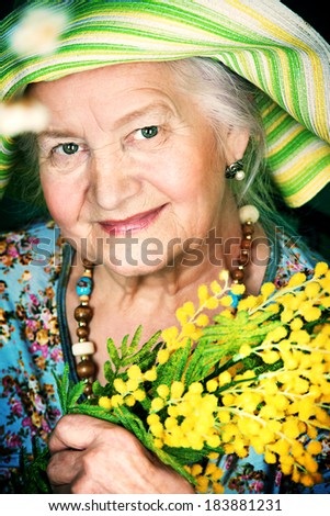 Portrait of a beautiful elderly woman with mimosa flowers. Happy old age.