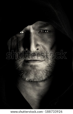 Portrait of a courageous warrior wanderer in a black cloak. Historical fantasy. Halloween. Black-and-white photo.