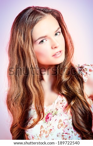 Beautiful girl with tender natural make-up and long hair posing over pink background.