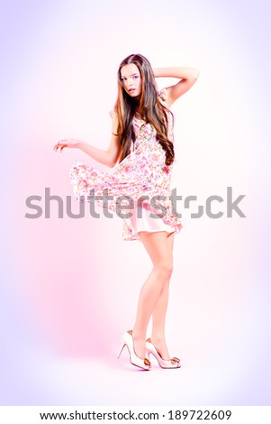Beautiful girl with natural make-up in a light summer dress posing over pink background. Fashion. Full length.