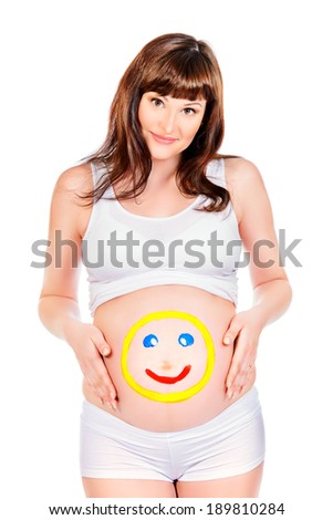 Smiling pregnant woman  with drawn funny face on her belly. Pregnancy. Healthcare. Studio shot.